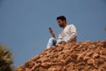 Young man using mobile phone sitting on a high wall