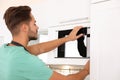 Young man using modern microwave oven Royalty Free Stock Photo