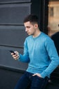 Young man is using the phone on the street. Handsome guy stand in front of window Royalty Free Stock Photo