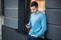 Young man is using the phone on the street. Handsome guy stand in front of window Royalty Free Stock Photo