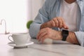 Young man using smart watch at table in kitchen, closeup Royalty Free Stock Photo