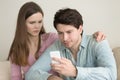 Young man using smartphone, having problems, girlfriend anxious Royalty Free Stock Photo