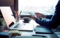 Young man using smartphone with modern work table and computer laptop and cityscapes view from window.Business concepts ideas.