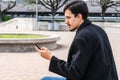 Young man using smartphone sitting in urban park Royalty Free Stock Photo
