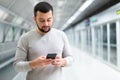 Young man using smartphone to check schedule on subway station Royalty Free Stock Photo