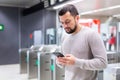 Young man using smartphone to check schedule on subway station Royalty Free Stock Photo