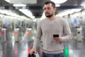 Young man using smartphone to check schedule on subway station Royalty Free Stock Photo