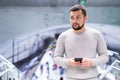 Young man using smartphone to check schedule on subway station Royalty Free Stock Photo