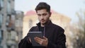 Young man using tablet outside. Hipster guy looking device screen outdoors.