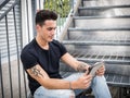 Young man using tablet PC sitting on metal stairs outside Royalty Free Stock Photo