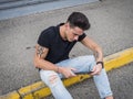 Young man using tablet PC sitting on street curb Royalty Free Stock Photo