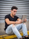 Young man using tablet PC sitting on street curb Royalty Free Stock Photo