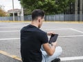 Young man using tablet PC sitting on street curb Royalty Free Stock Photo