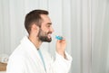 Young man using teeth whitening device at home. Royalty Free Stock Photo