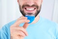 Young man using teeth whitening device on light background Royalty Free Stock Photo