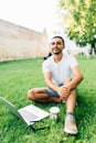 Young handsome man using and typing laptop computer in summer grass. Royalty Free Stock Photo