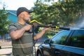 Young man using a water gun to wash his car. Male driver washing a car with contactless high pressure water jet Royalty Free Stock Photo