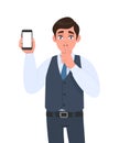 Young man in vest suit showing mobile, cell or smartphone and asking silence gesture sign with finger on lips. Keep quiet. Sh! Royalty Free Stock Photo