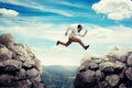 Young man in virtual reality headset jumping between two high rocks Royalty Free Stock Photo