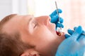 Young man visiting the dental office. Dentist hands in protective gloves using ultrasound to clean patient`s teeth Royalty Free Stock Photo