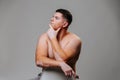 Young man vitiligo in studio shot gray background poses with please one hand on face other on face.