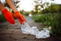 Young man volunteer picks up trash at the park. Plastic bottle is being collected by the man wearing orange gloves. Pollution, Royalty Free Stock Photo