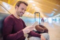 Young man waiting using mobile phone at the airport with a suitcase Royalty Free Stock Photo