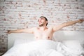 Young man waking up in bed and stretching his arms in the morning Royalty Free Stock Photo