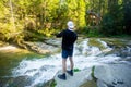 Young man walk near fast river in forest