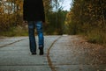 Young man walk on panel path in autumn forest, colored photo