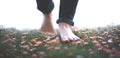 A young man walking barefoot.in a meadow full of flowers Close-up photograph of the lower leg and bare feet trampling