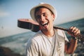 Young man walking on the beach holding a guitar in his hands Royalty Free Stock Photo