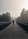 Young man walking on bridge over river Vltava in city Ceske Budejovice with fog