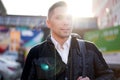 Young man walking in city during day, lensflare effect.