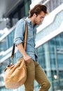 Young man walking in the city with travel bag Royalty Free Stock Photo