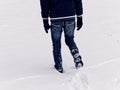 Backside of young man walking through deep snow