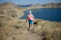 Young man walking down the hill to a mountain shore alone