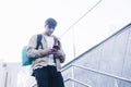 Young man walking down stairs with backpack while using mobile outdoors Royalty Free Stock Photo