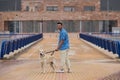 Young man walking with his brown Labrador retrieve dog. The photo is taken from behind. And in the background a building. Concept