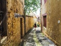 Young man walking in a narrow alley in the city center of the medieval village of Gourdon in Lot, France Royalty Free Stock Photo