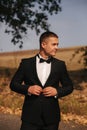 Young man walking in the park. Handsome groom in black suit