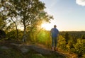 Young man walking on rock with tree with sun rays shine. Ore mountain, Czech landscape Royalty Free Stock Photo