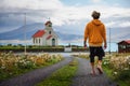 Young man walking towards a church and a cemetery in Iceland