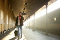 Young man walking at train station with bag and mobile phone Royalty Free Stock Photo