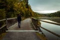 Young man walking on wooden bridge with Vltava river and autumn trees