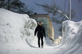 A young man walks along a snow-covered sidewalk among large snowdrifts Royalty Free Stock Photo