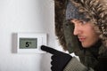 Man In Warm Clothing Pointing To Current Room Temperature