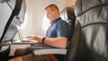 A young man was sitting on the plane and working on his laptop before departure. Royalty Free Stock Photo