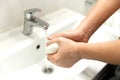 A young man washes his hands with soap