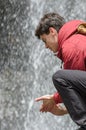 Young man washes his hands in a waterfall